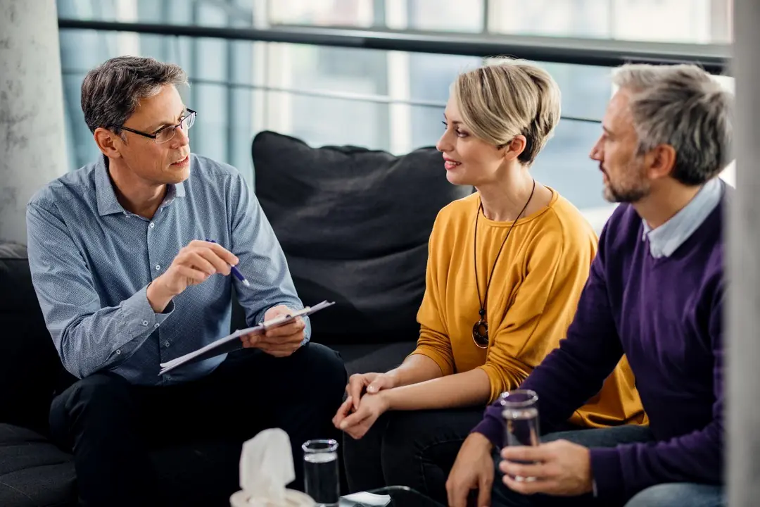 Psychotherapeut im Gespräch mit zwei Personen in einer Praxis